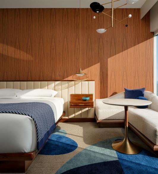 A bed with a wooden wall behind it and a sofa next to the bed