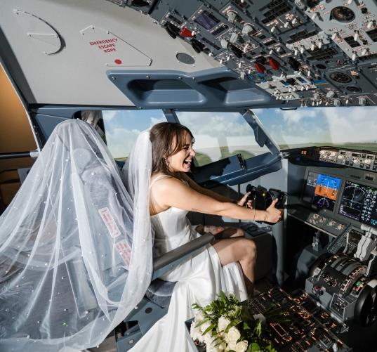 A bride wearing her dress while in the flight simulator