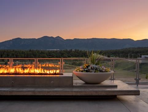 A plant next to a fireplace on a terrace that overlooks the valley at sunset