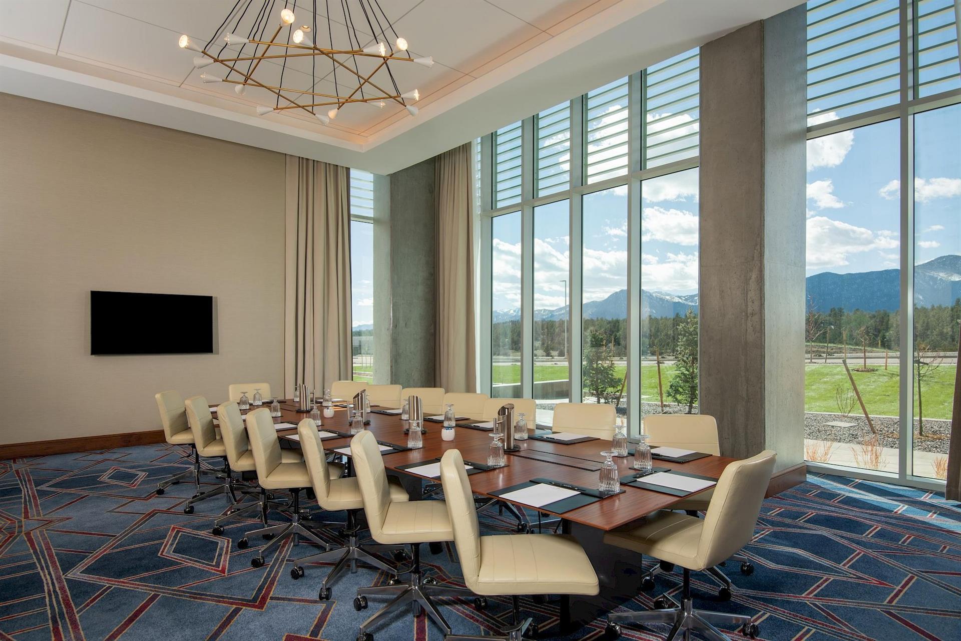 Executive boardroom at Hotel Polaris featuring a conference table, modern seating, floor-to-ceiling windows, state-of-the-art technology, and panoramic views of the Rocky Mountains.