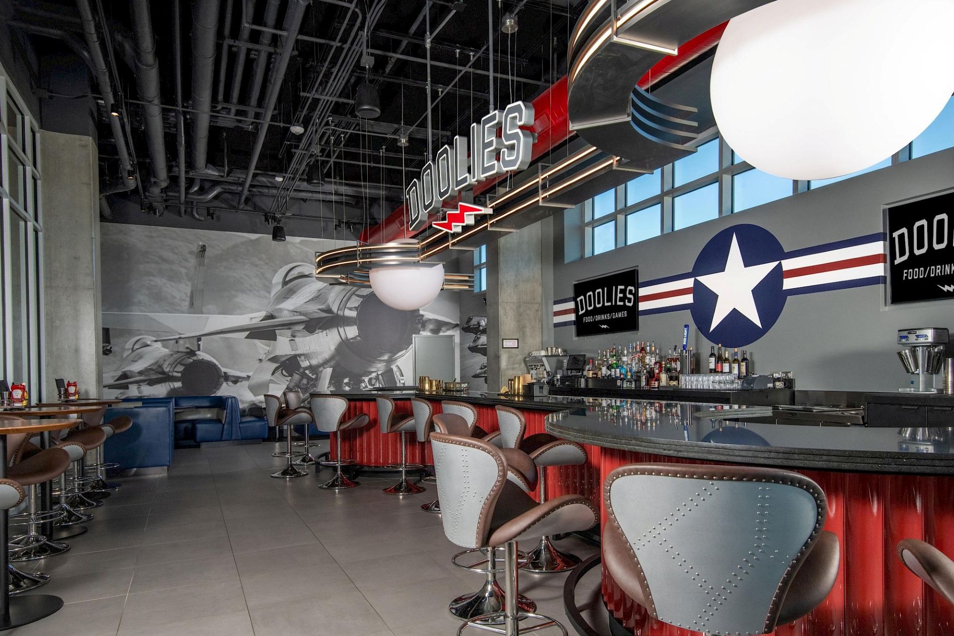 Aviation-themed sports bar with red bar counters, aircraft-inspired seating, large jet mural, military-style star graphic, and Doolies signage.