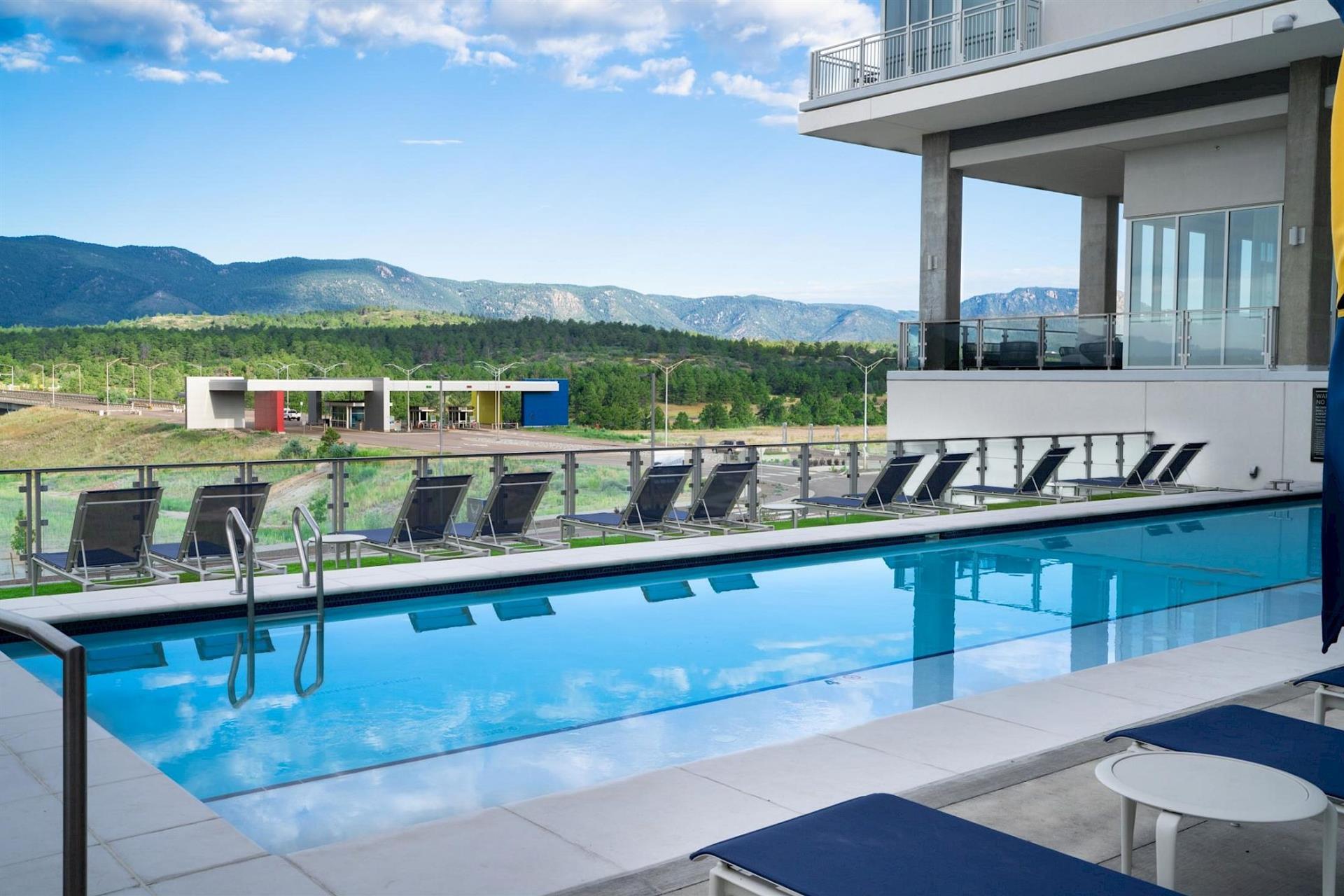 Outdoor pool at Hotel Polaris featuring lounge chairs, mountain views, and a spacious pool deck overlooking the U.S. Air Force Academy and the Rocky Mountains.