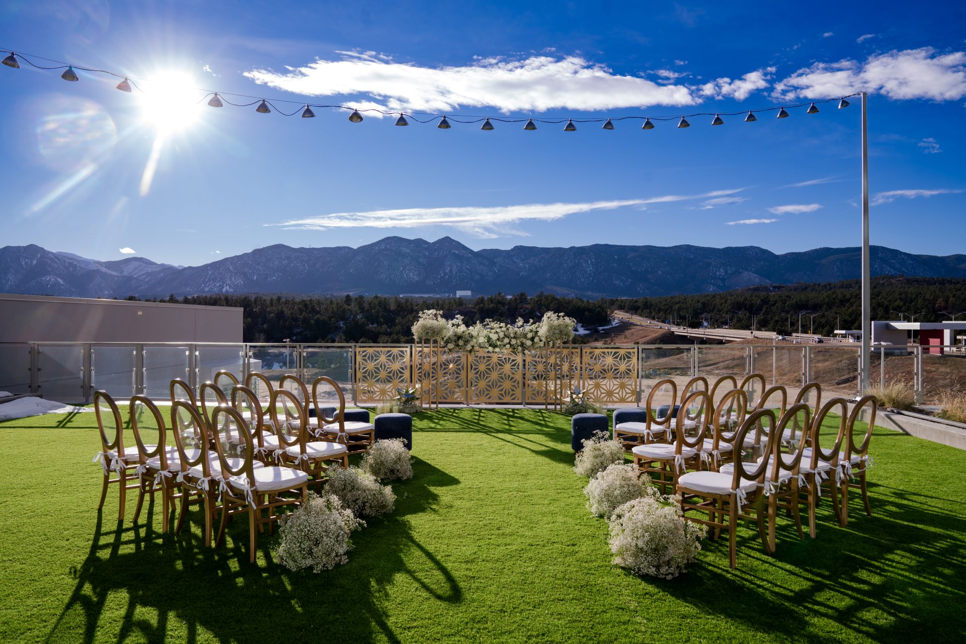 Rooftop wedding ceremony setup at Hotel Polaris featuring rows of gold chairs, white floral arrangements, and mountain views beneath a bright blue Colorado sky.