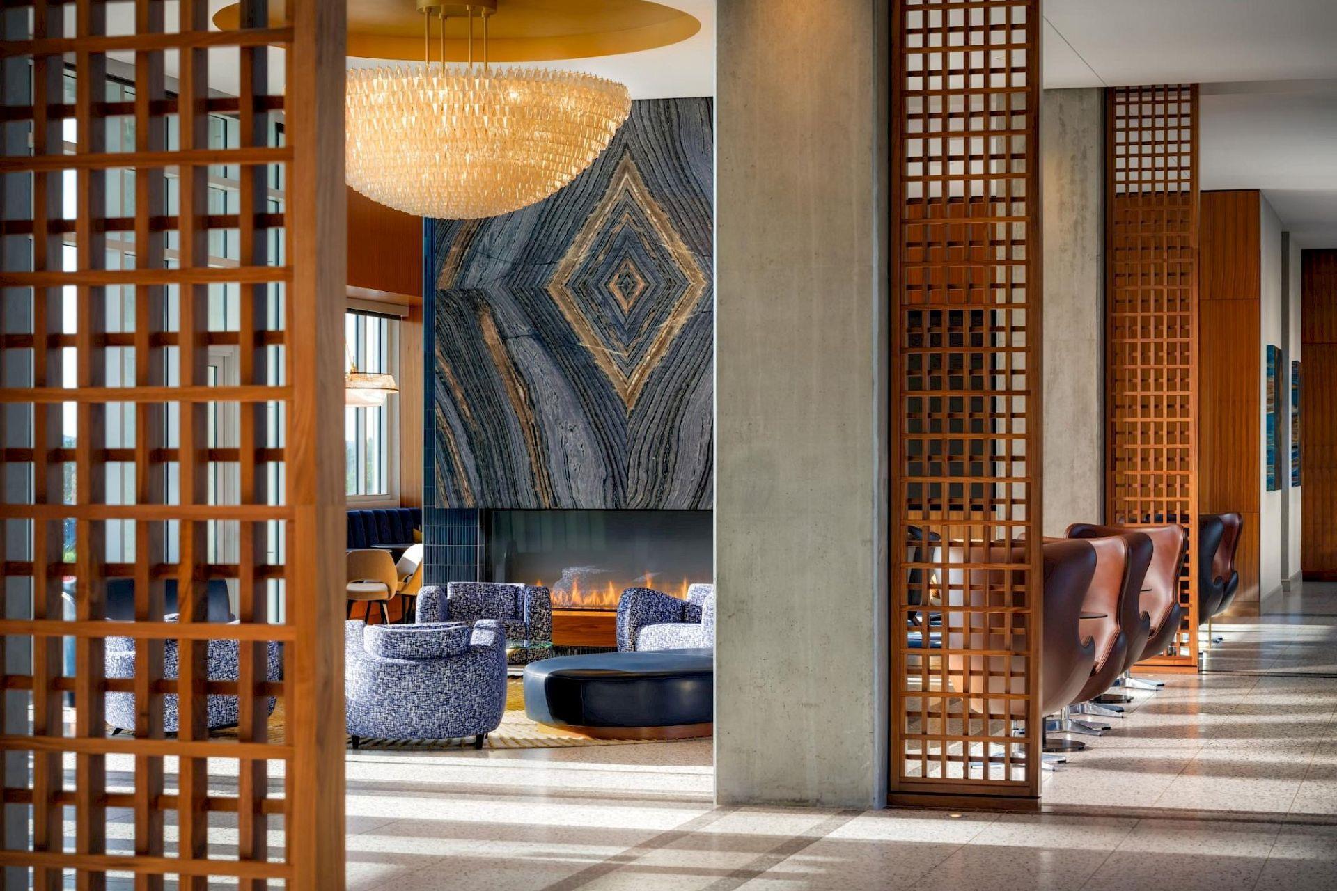 Hotel Polaris lobby lounge with blue seating, a dramatic stone fireplace, chandelier, and warm wood accents.