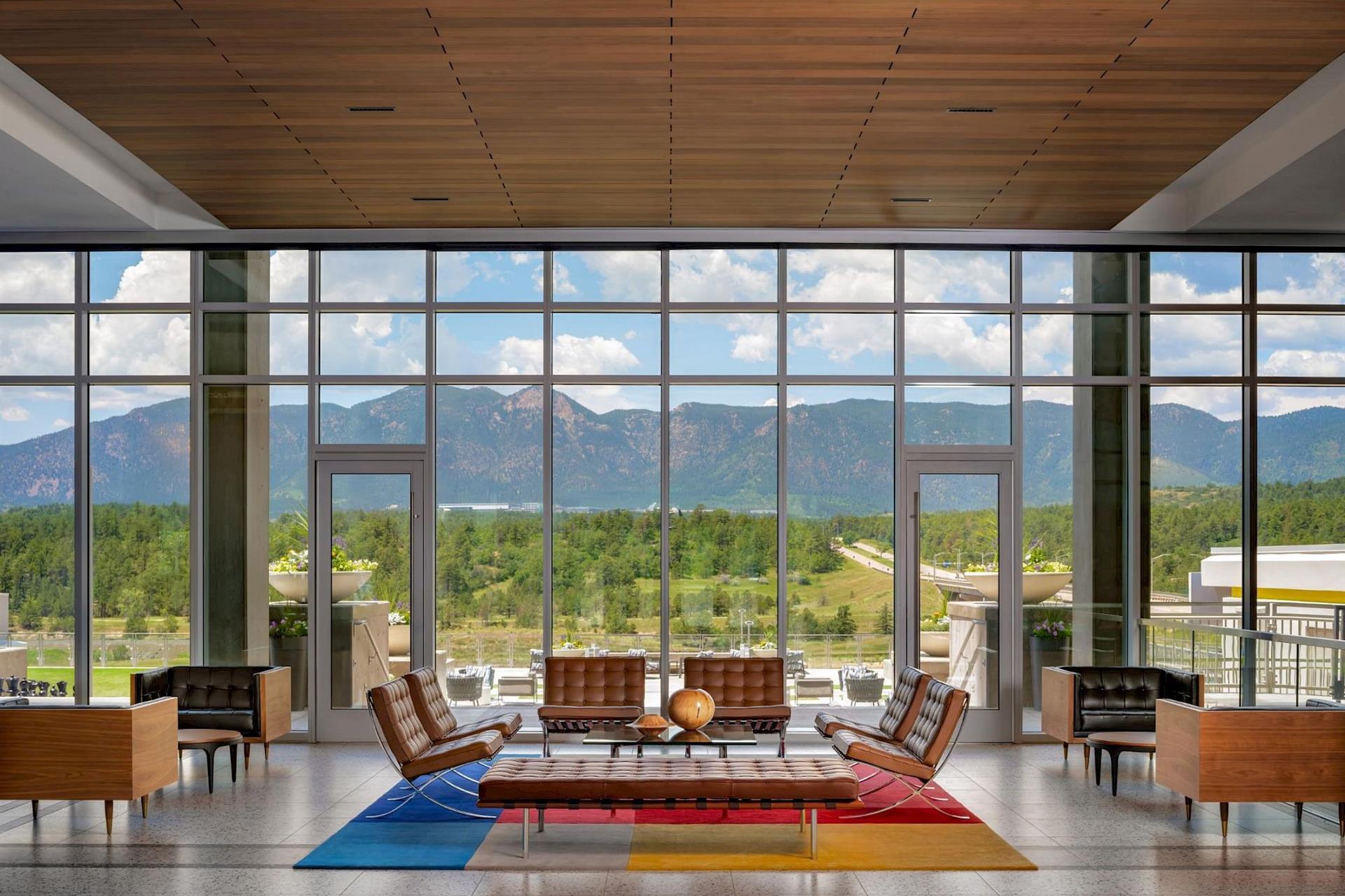 Hotel Polaris lobby featuring floor-to-ceiling windows, mid-century-inspired lounge seating, and panoramic views of the Rocky Mountains and surrounding Colorado landscape.