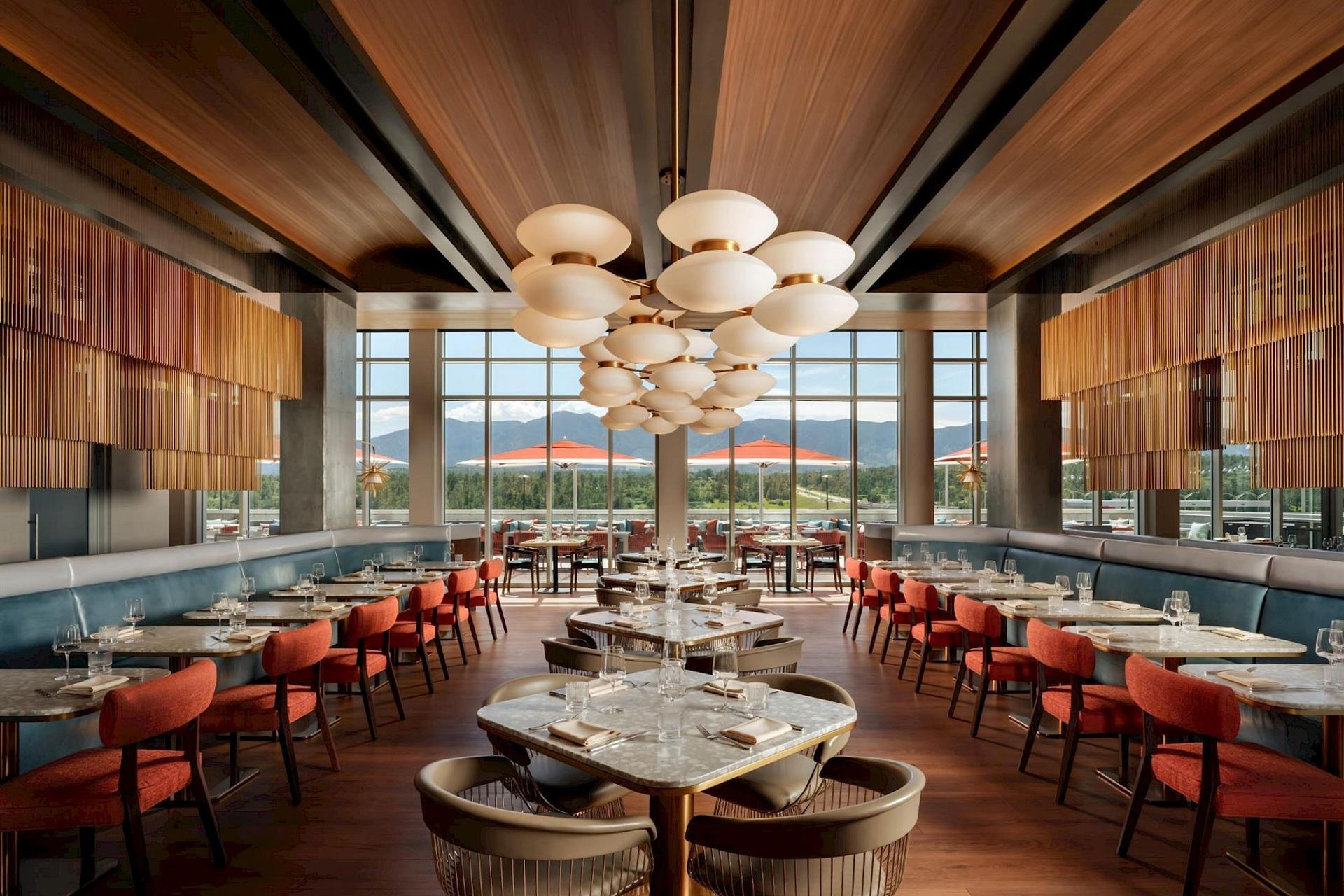 Modern restaurant at Hotel Polaris featuring contemporary dining tables, floor-to-ceiling windows, elegant lighting, and sweeping views of the Rocky Mountains.
