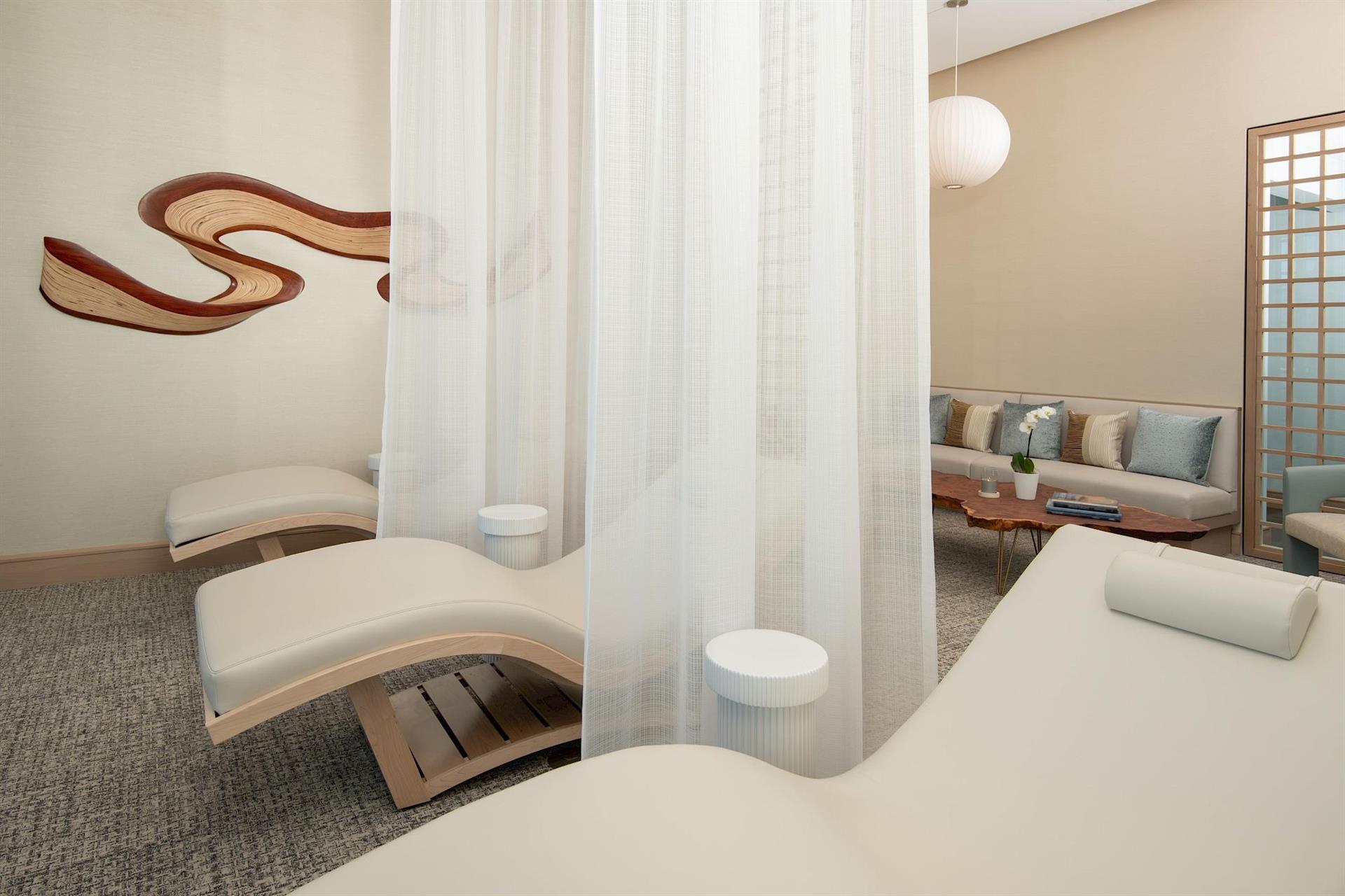 Relaxation lounge at Hotel Polaris' spa featuring plush reclining chairs, soft privacy curtains, contemporary seating, and a serene atmosphere designed for rest and wellness.