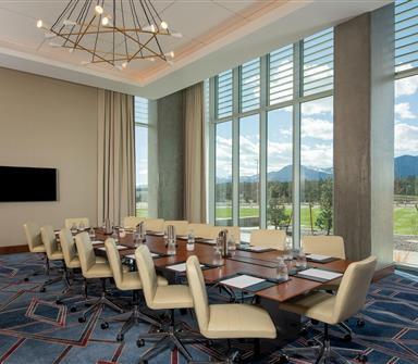 Executive boardroom at Hotel Polaris featuring a conference table, modern seating, floor-to-ceiling windows, state-of-the-art technology, and panoramic views of the Rocky Mountains.