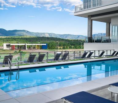Outdoor pool at Hotel Polaris featuring lounge chairs, mountain views, and a spacious pool deck overlooking the U.S. Air Force Academy and the Rocky Mountains.