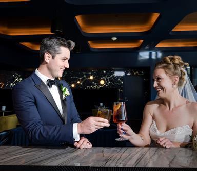 Bride and groom toasting cocktails at The Aviator rooftop bar at Hotel Polaris, celebrating their wedding in an elegant aviation-inspired setting.