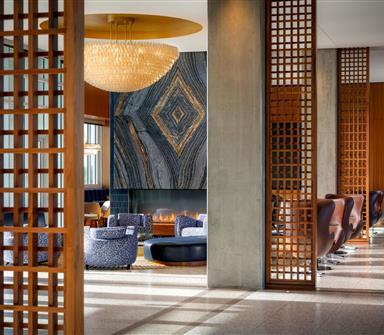 Hotel Polaris lobby lounge with blue seating, a dramatic stone fireplace, chandelier, and warm wood accents.