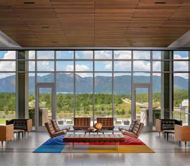 Hotel Polaris lobby featuring floor-to-ceiling windows, mid-century-inspired lounge seating, and panoramic views of the Rocky Mountains and surrounding Colorado landscape.