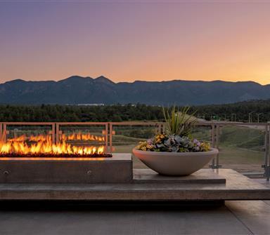 Outdoor fire feature and floral planter at Hotel Polaris overlooking the mountains at sunset.
