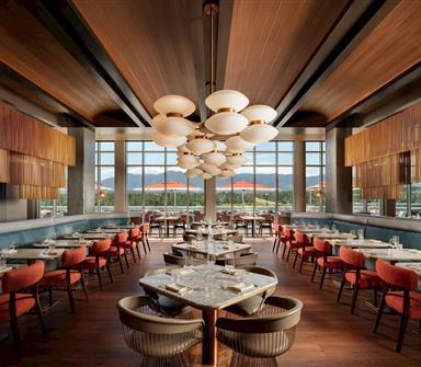 Modern restaurant at Hotel Polaris featuring contemporary dining tables, floor-to-ceiling windows, elegant lighting, and sweeping views of the Rocky Mountains.
