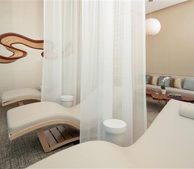 Relaxation lounge at Hotel Polaris' spa featuring plush reclining chairs, soft privacy curtains, contemporary seating, and a serene atmosphere designed for rest and wellness.