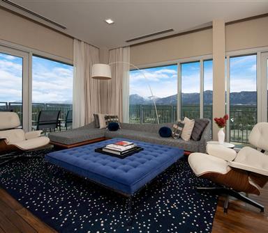 Luxury suite living room at Hotel Polaris featuring contemporary furnishings, floor-to-ceiling windows, a private balcony, and sweeping views of the Rocky Mountains.