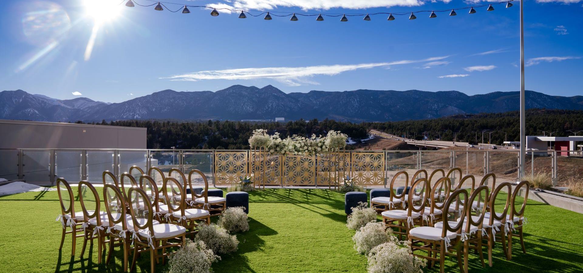 An outdoor event space with a grassy area, rows of chairs, and a mountain view.